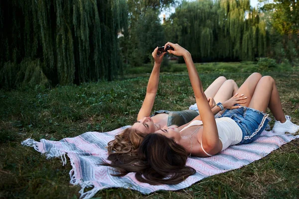 Dos Hermanas Acostadas Sobre Una Manta Césped Parque Atardecer Tomando — Foto de Stock