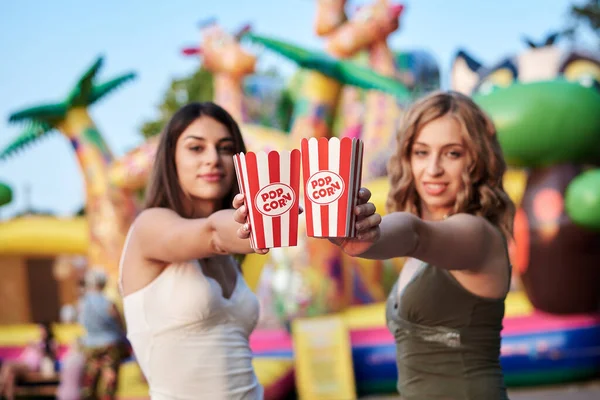 Två Systrar Stående Framför Attraktion Nöjesparken Håller Popcorn Papperslådan Ler — Stockfoto