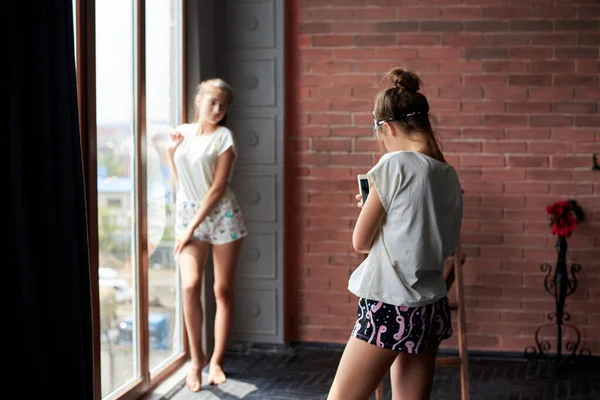 Молодая Брюнетка Короткой Пижаме Фотографируется Телефоном Своей Девушки Которая Стоит — стоковое фото