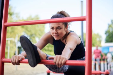 Siyah formalı, esmer bir kadın. Yaz aylarında İsveç Gölü 'nün yanındaki duvarda esneme egzersizleri yapıyor. Sporcu kadın dışarıda antrenman yapıyor. Sağlıklı enerjik yaşam tarzı kavramı.