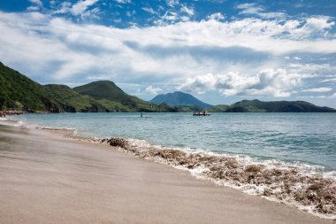 St. Kitts Adası / Saint Kitts ve Nevis - 29 Kasım 2016: Arkasında dağlar olan siyah kum plajı manzarası. Güzel seyahat filmi.