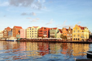 Willemstad / Curacao - 15 Kasım 2016: Curacao Adası 'ndaki renkli Hollanda binaları ile Willemstad limanının manzarası. Güneşli havalarda sudaki güzel evlerin parlak yansıması..