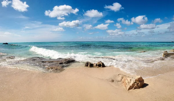 ライトブルーの空 ターコイズブルーの水と白い雲を持つカリブ海の海岸でのロッキービーチの景色 岩や海で巨大な泡立つ波と日当たりの良いビーチの風景 パノラマの熱帯の風景 — ストック写真