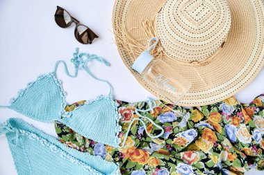 Beyaz arka planda izole edilmiş yaz tatili plaj aksesuarlarının düz bir resmi vardı. Nane mavisi mayo, güneş gözlüğü, renkli çiçekli eşarp, bir şişe su Mutlu işareti ve hasır şapka.