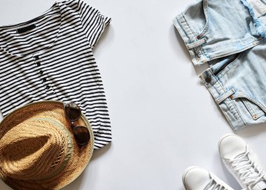 Beyaz arka planda izole edilmiş yaz kıyafetlerinin düz bir resmi vardı. Hasır şapka, güneş gözlüğü, çizgili siyah beyaz tişört, açık mavi kot şort ve beyaz spor ayakkabı. Yaz tatili geçmişi.