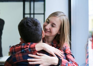 Sarışın, güzel bir kadın, esmer adama sarılıyor, sırtı kameraya dönük. Romantik bir çift, kırmızı kareli gömlekler giyiyorlar, bir kahve dükkanının penceresinde oturuyorlar. Gülümsüyor. Romantik Sevgililer Günü.