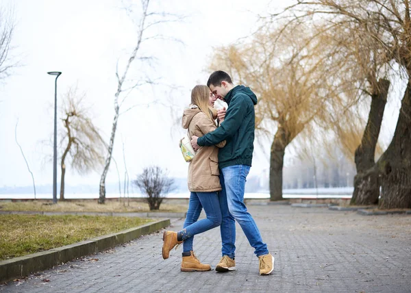 在春天里的城市公园里 一对年轻夫妇相亲相爱 站在那里 拥抱在一起 穿着休闲装和牛仔裤 情人节在城外举行浪漫的庆祝活动 — 图库照片