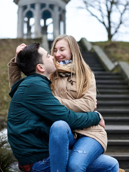 若いブロンドの女性は ブルネットの男の膝の上に座って 互いに抱き合って 古い階段でキスをしています ロマンチックなバレンタインデーのお祝い — ストック写真