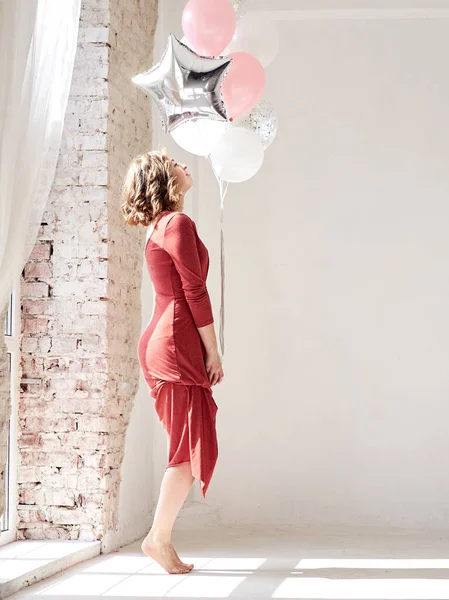 Kısa Kıvırcık Saçlı Kırmızı Elbiseli Dans Eden Pembe Gümüş Balonları — Stok fotoğraf