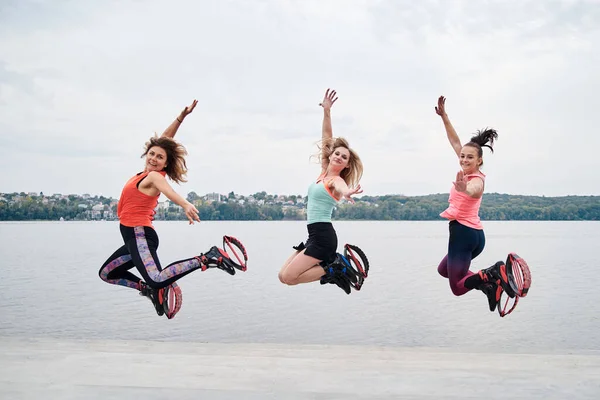Grupo Jovens Encaixam Mulheres Magras Saltos Kangoo Pulando Frente Lago — Fotografia de Stock