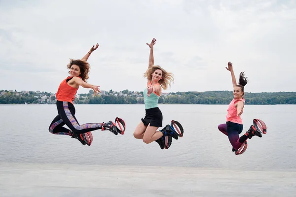 Grupo Jovens Encaixam Mulheres Magras Saltos Kangoo Pulando Frente Lago — Fotografia de Stock