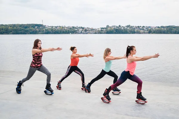 Grupo Jovens Encaixam Mulheres Magras Saltos Kangoo Treinando Frente Lago — Fotografia de Stock