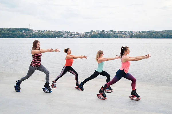 Grupo Jovens Encaixam Mulheres Magras Saltos Kangoo Treinando Frente Lago — Fotografia de Stock