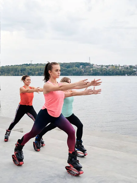 Grupo Jovens Encaixam Mulheres Magras Saltos Kangoo Treinando Frente Lago — Fotografia de Stock