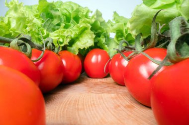 Ahşap masa arka plan üstüne marul yaprakları ile kırmızı neşeli domates. Evde yetiştirilen sebzeler, sağlıklı beslenme yaşam tarzı