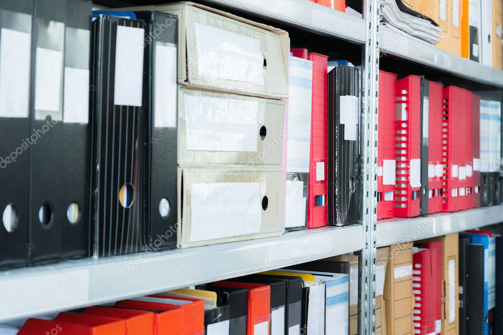 Colourful blank blind folders with files in the shelf. Archival, stacks of documents at the office or library. Physical document storage units