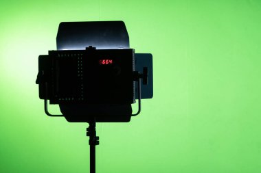 Stüdyo ışıkları arka planda yeşil ekran ile parlıyor. Reklam işi, sinema filmi, yeşil televizyon arkaplanı için spot lambası silueti