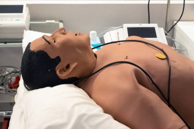 Pratik için oyuncak bir bebeğin üzerinde defibrilatör var. Hastanede eğitim amaçlı suni teneffüs mankeni. Tıp öğrencileri için ilk yardım eğitimi sınıfı