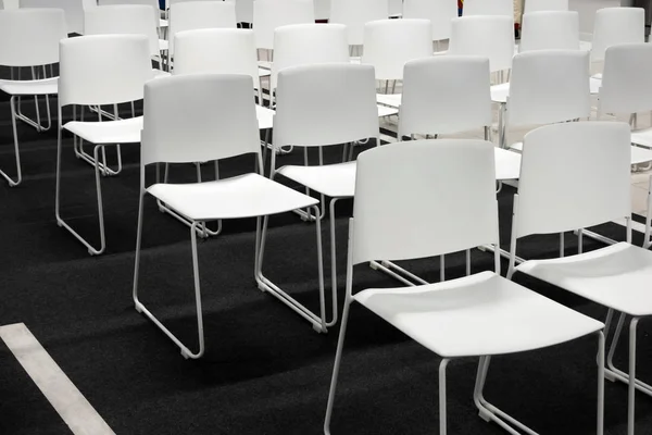 Filas de sillas de plástico blanco para reuniones formales, conferencias, conferencias, ceremonias de graduación. Habitación llena de sillas blancas vacías . —  Fotos de Stock