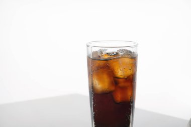 Buzlu soğuk, ferahlatıcı kola bardağı beyaz zemin üzerinde ve metin için yer var. Kafeinli soğuk bir içecek.