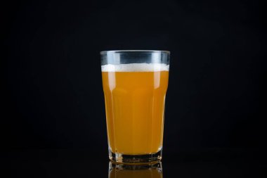 Taze ve soğuk cam bira, üzerine beyaz köpük, üzerine siyah arka plan ve metin için yer. Koyu arkaplanda köpüklü buğday ya da bira