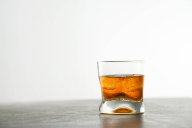 Masasında buz küpleri olan bir bardak yıllanmış altın viski. Kehribar boyalı içki ve bardaki taşlar.