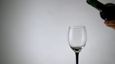 Beyaz arka planda bir bardağa kırmızı şarap dökülüyor. Şarap kadehi alkolle dolu, arka planda içki.