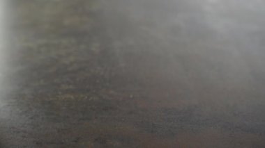 Bir bardak buzlu altın viski içen ve masaya koyan adam. Kehribar renginde, kayalık arkaplanlı alkol içeceği.
