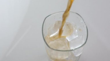 Soğuk, ferahlatıcı kola beyaz arka planda buzlu bardağa doluyor ve metin için yer var. Kafeinli soğuk bir içecek.