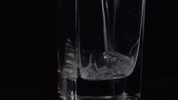 Verser de l'eau minérale fraîche dans du verre sur une table. Boisson pétillante fraîche avec boules d'oxygène sur fond noir 