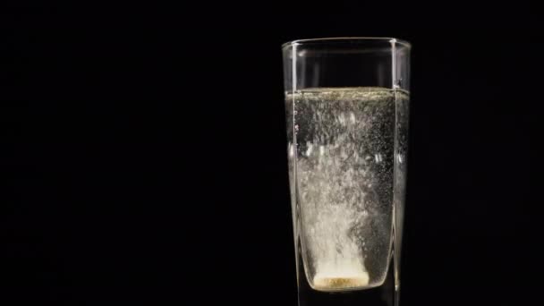 Comprimé de vitamine C se dissolvant dans un verre d'eau plate minérale fraîche sur fond sombre. Pilule bouillonnante dans un liquide avec des boules d'oxygène sur fond noir 