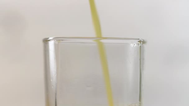 テーブルの上にグラスに注ぐ新鮮な絞りオレンジジュース 白を基調とした黄色の飲み物 — ストック動画