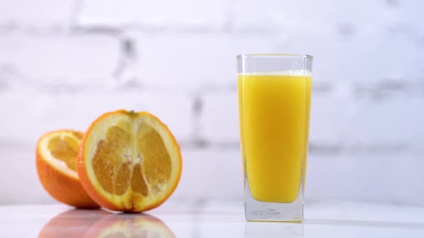 Jugo Naranja Recién Exprimido Vaso Sobre Una Mesa Con Rodajas — Vídeos de Stock
