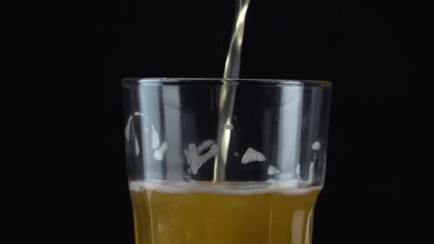 黒を基調とした泡の白いガラスに 新鮮で冷たいクラフトビールを注ぐ 暗い背景に泡状の小麦やラガービールを流れる — ストック動画