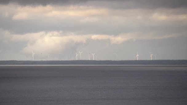 风车在地平线上 云彩在晴朗的天空中 大海在前景中 风力涡轮机 发电的风力发电场 绿色能源 — 图库视频影像