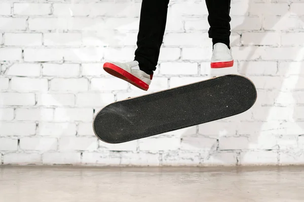 Скейт-ардер, выполняющий скейт-трюк - удар ногой по бетону. Олимпийский спортсмен практикует прыжок на белом фоне, готовится к соревнованиям. Экстремальный спорт, молодежная культура, городской спорт — стоковое фото