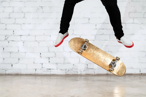 Skateboarder eseguire trucco skateboard - calcio flip sul calcestruzzo. Atleta olimpico che pratica il salto su sfondo bianco, preparandosi alla competizione. Sport estremi, cultura giovanile, sport urbano — Foto Stock