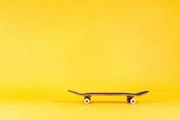 Professionell skateboard isolerad på gul bakgrund. Ateljéfoto av skateboard, ungdomshobby. Olympisk sport. Kopiera utrymme för text — Stockfoto