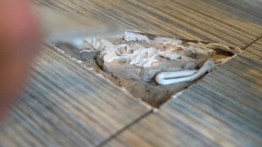 Close up view of man fixing broken tile in the bathroom. Hands renovate cracked asbestos floor tile. Damaged ceramic tile