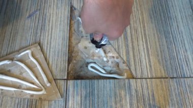 Close up view of man fixing broken tile in the bathroom. Hands renovate cracked asbestos floor tile. Damaged ceramic tile