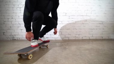 Beyaz tuğla bir duvarın yanında duran kaykaycı. Kaykaylı kot giyen atletik bir genç. Şehir tarzı, gençlik kültürü