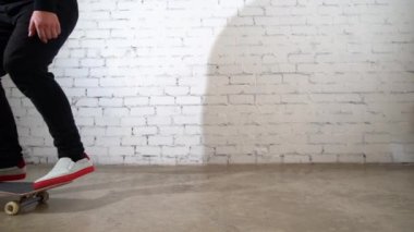 Kaykaycı kaykay numarası yapıyor. Betona tekme atarak. Beyaz arka planda atlama antrenmanı yapan sporcu, yarışmaya hazırlanıyor. Aşırı spor, gençlik kültürü