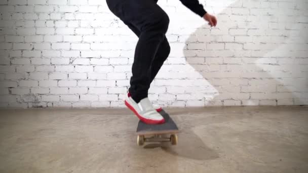 スケートボードのトリックを実行するスケートボーダー 具体的にキックフリップ 選手は白を背景にジャンプ練習を行い 競技の準備をする 極端なスポーツ 若者文化 — ストック動画