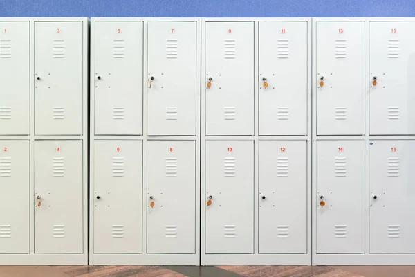 Ряд серых металлических шкафчиков школы с ключами в дверях. Кладовая в коридоре учебного заведения — стоковое фото