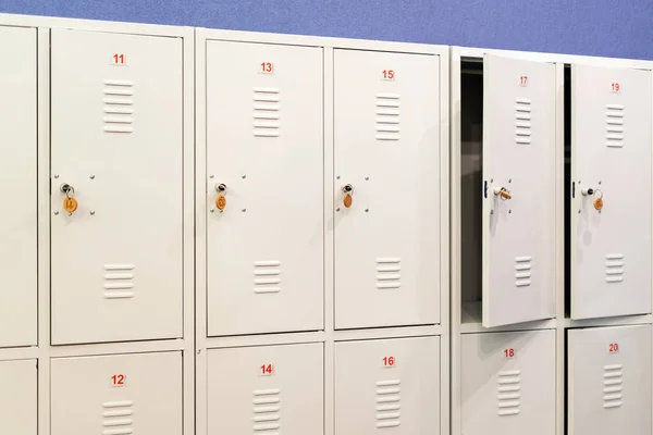 A row of grey metal school lockers with keys in the doors. Storage locker room in corridor of educational institution — Stock Photo, Image