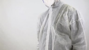 Tam takım elbiseli ve maskeli bir doktor beyaz arka planda eli ile dur işaretini gösteriyor. Corona virüsü veya covid-19 küresel salgın