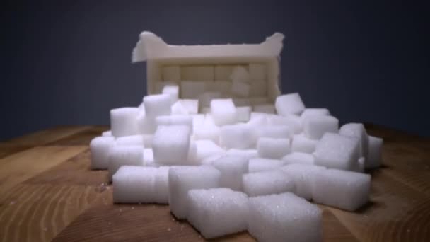 木製のテーブルのカートンボックスの隣に砂糖キューブを滑空のマクロドリーショット 不健康な食品甘味料 甘い結晶キューブ — ストック動画