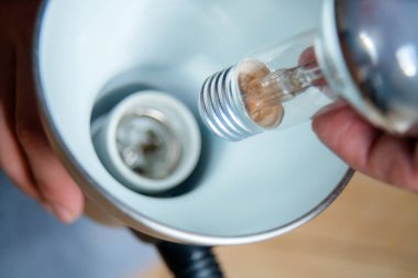 Lambanın üzerindeki ampulü değiştiren elleri kapatın. Tamirci floresan ışığı kuruyor, lambayı değiştiriyor