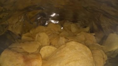 Patates cipsi paketinin içinde kayan kameranın Dolly görüntüsü. Orijinal bir paket lezzetli patates cipsi. Fast food ve sağlıksız yeme konsepti