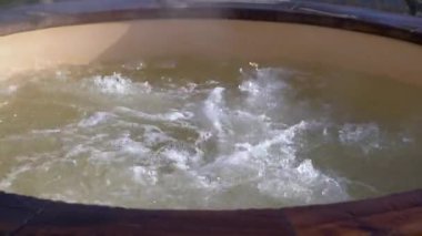 Dışarıdaki ahşap jakuzide su nasıl da kıvrılıyor. Güneşli bir günde sıcak havuzun tadını çıkarmak, özel spa tedavisi. Kimse.